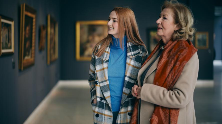 Grandmother and granddaughter looking at paintings in an art gallery 